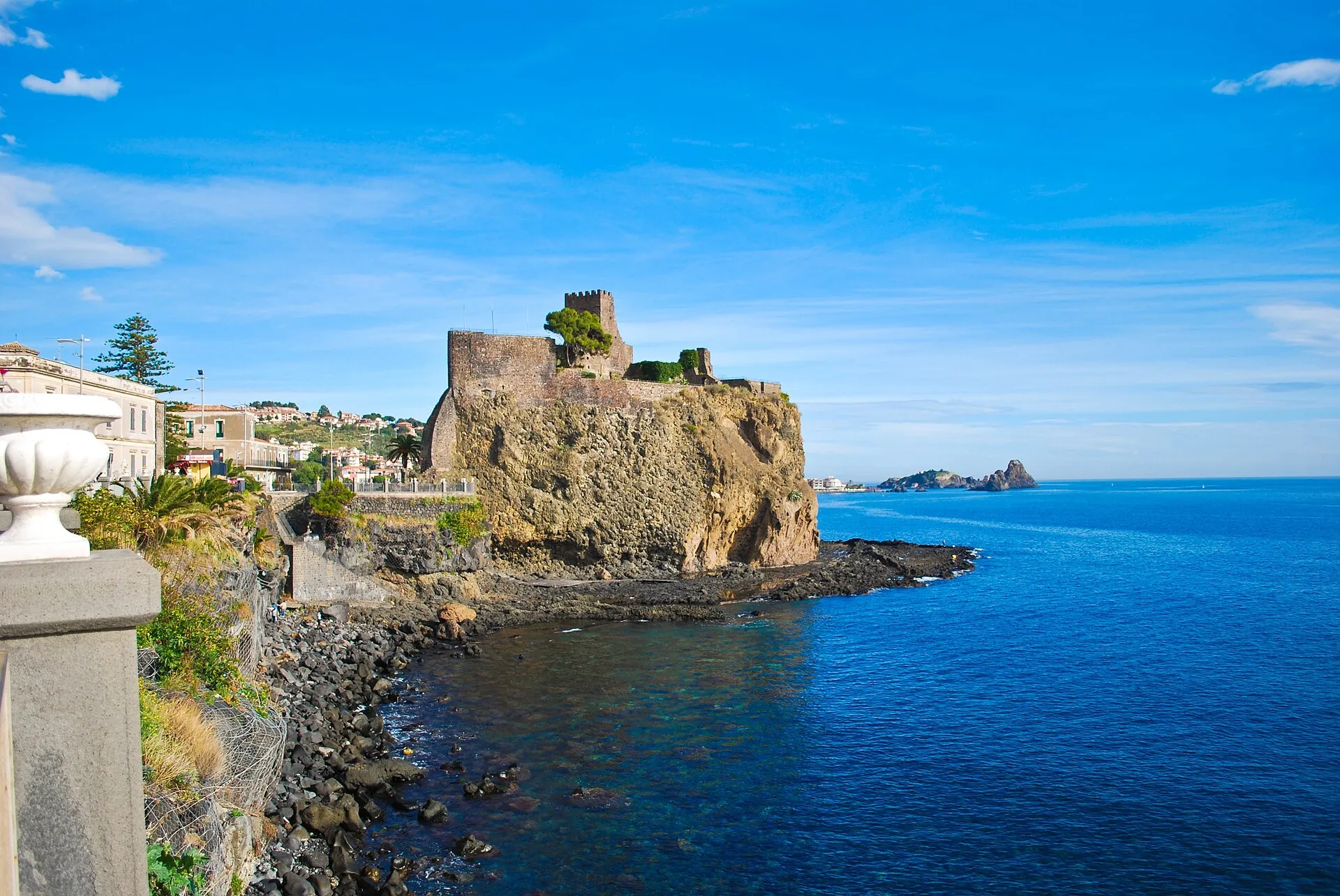 Il castello normanno di Aci Castello sulla sua roccia sul mare, con in fondo i faraglioni di Aci Trezza