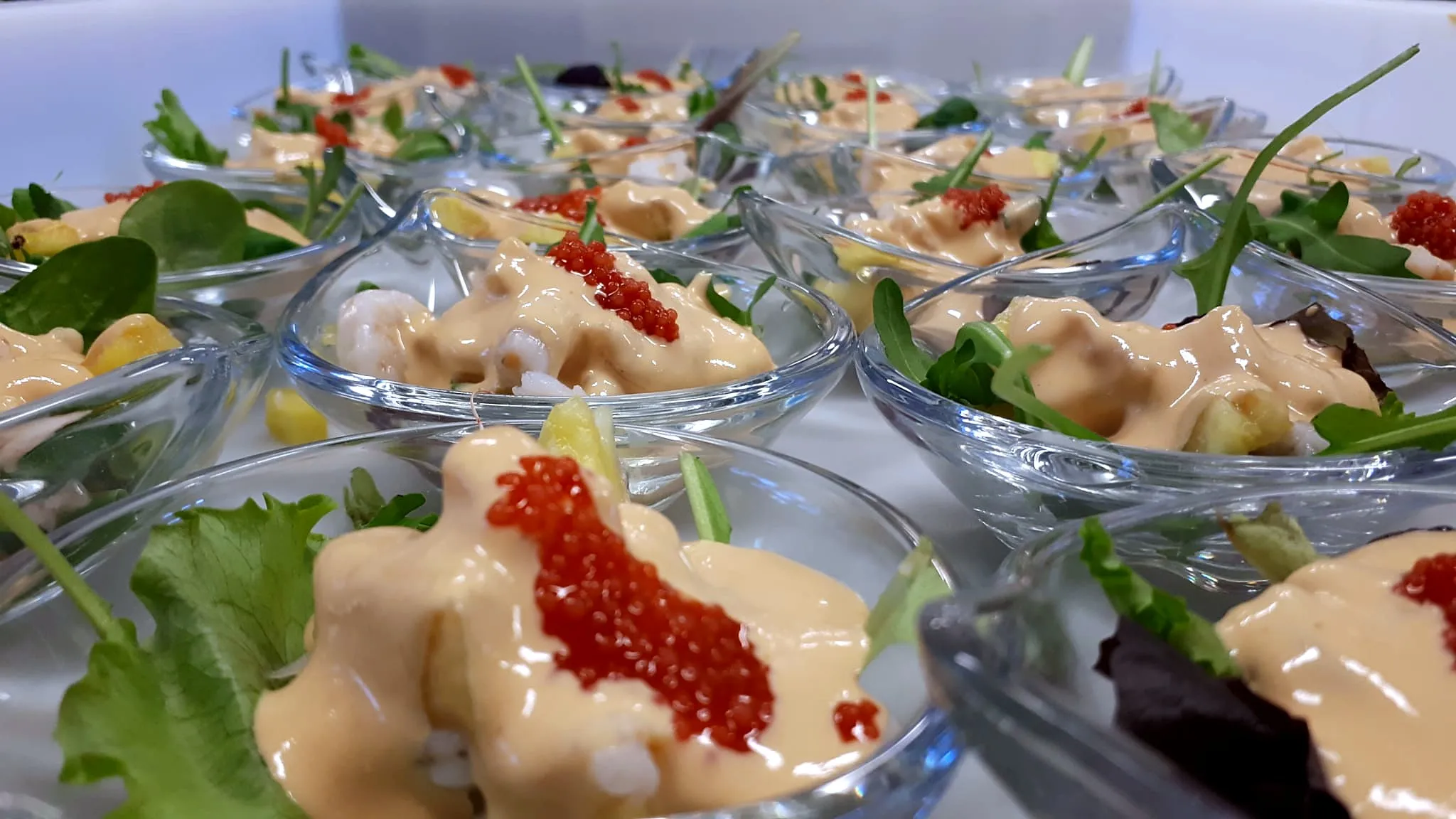 Coppette di vetro con gamberi in salsa, uova di salmone e insalatina