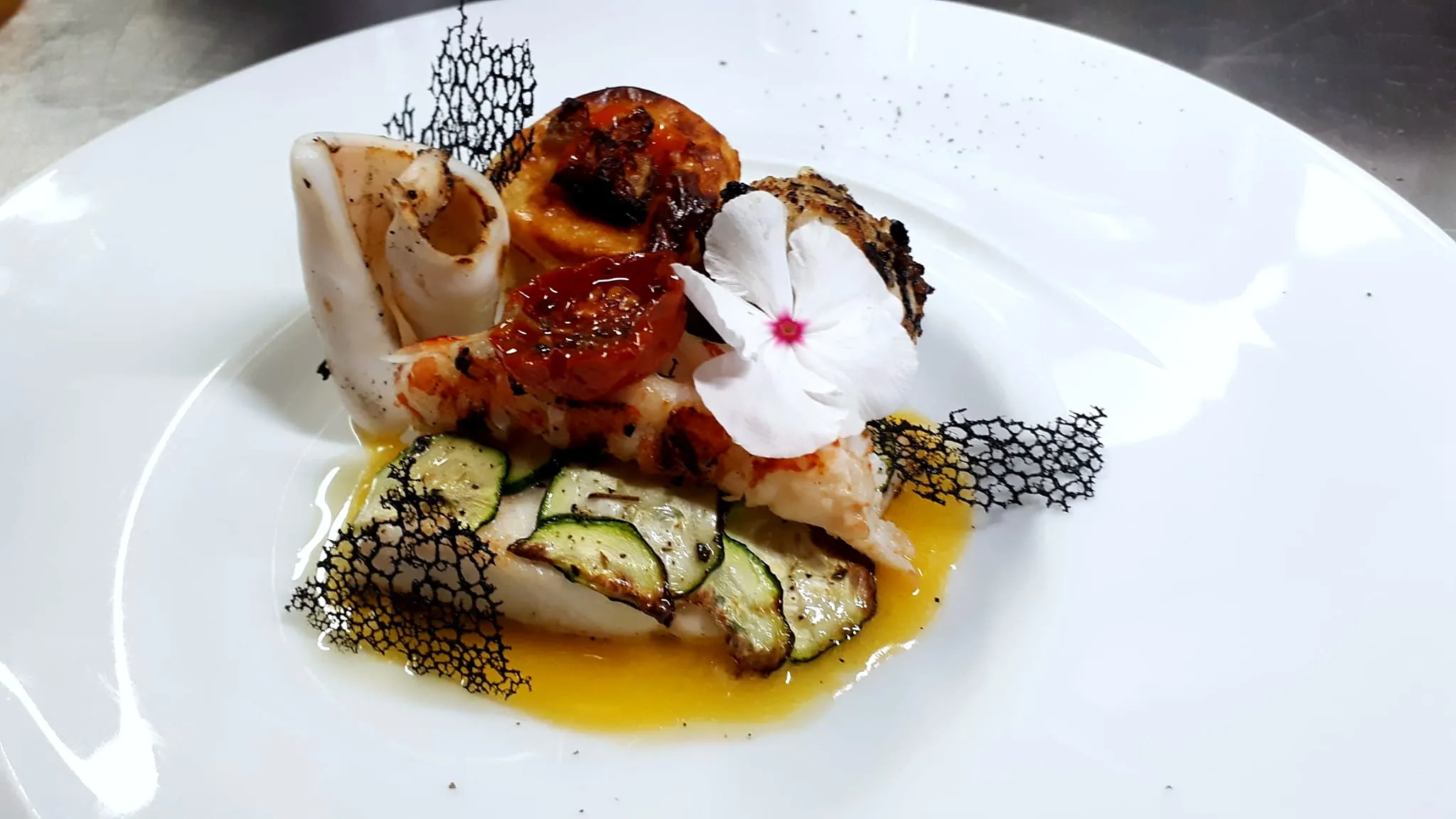 Pesce alla griglia con zucchine, pomodorini confit e un fiore
