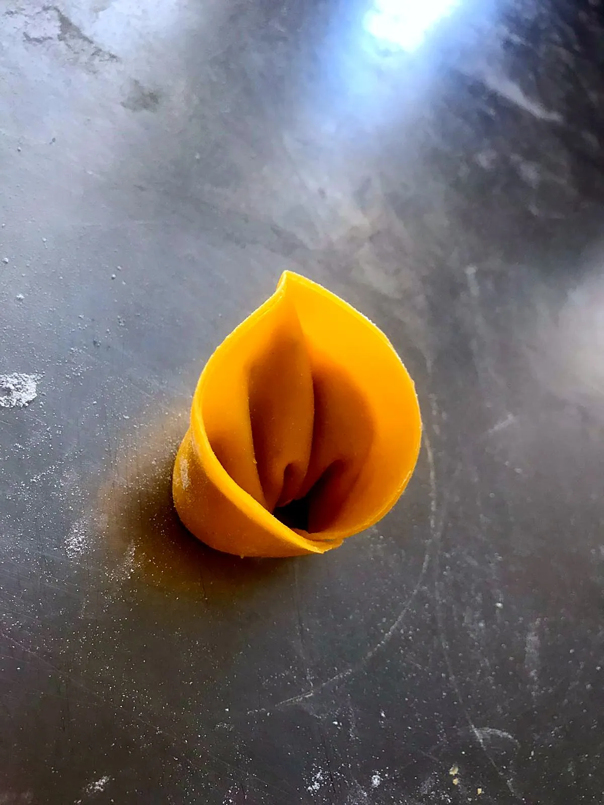Un tortello di pasta fresca sul banco d'acciaio della cucina